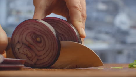 Woman-cutting-red-onion-on-wooden-board